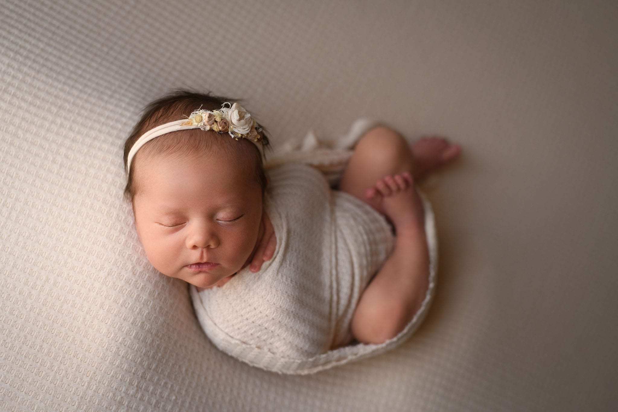 Newborn sleeping peacefully in swaddle with flower headband after mom used Denver prenatal yoga.